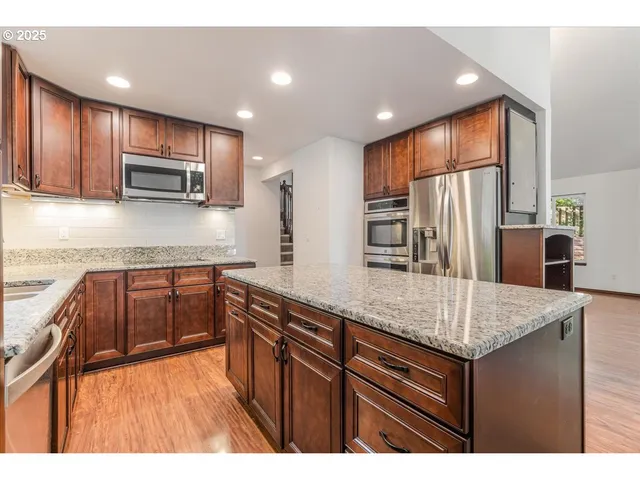 a kitchen with stainless steel appliances granite countertop a refrigerator and a sink
