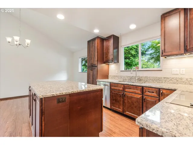 a kitchen with stainless steel appliances granite countertop wooden cabinets a stove top oven a sink and dishwasher