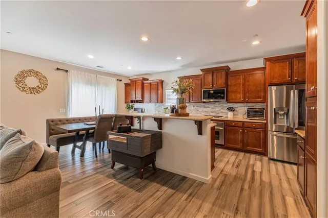 a kitchen with stainless steel appliances a refrigerator a stove a sink dishwasher and a dining table with wooden floor