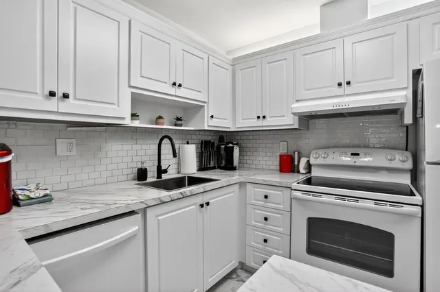 a kitchen with granite countertop white cabinets and stainless steel appliances