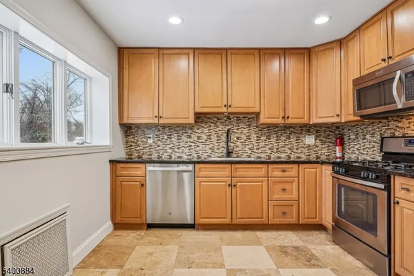 a kitchen with stainless steel appliances granite countertop a stove a sink and a microwave