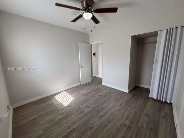 an empty room with wooden floor ceiling fan and windows