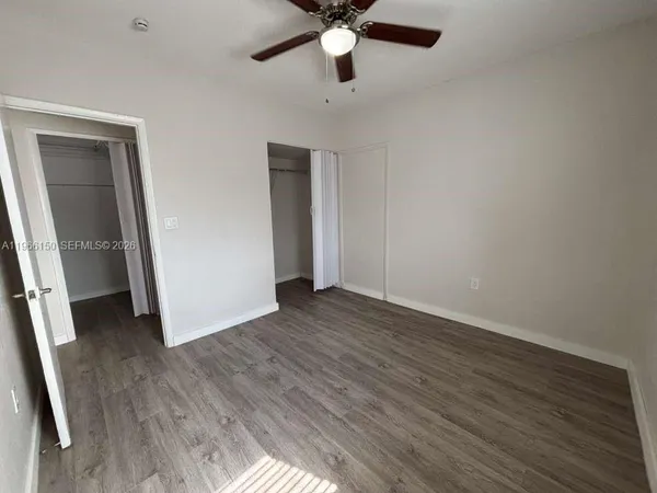 an empty room with wooden floor and ceiling fan