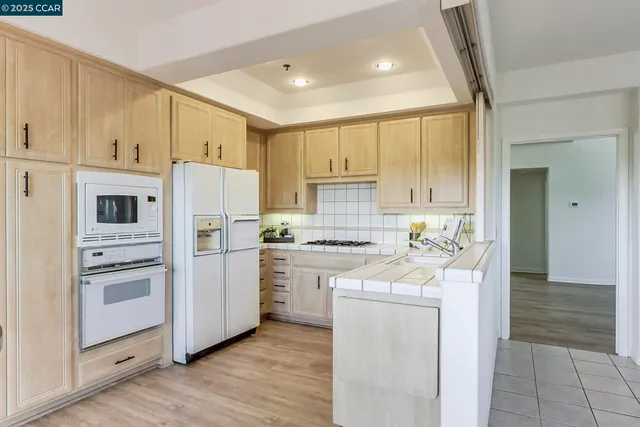 a kitchen with stainless steel appliances granite countertop a refrigerator a stove and white cabinets