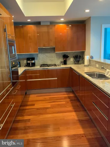 a large kitchen with stainless steel appliances granite countertop a sink and wooden cabinets