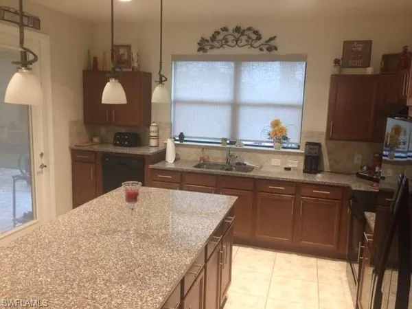 a kitchen with kitchen island granite countertop a sink a counter top space and cabinets