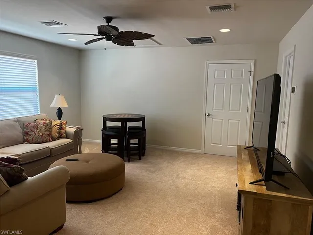 a living room with furniture a ceiling fan and a window