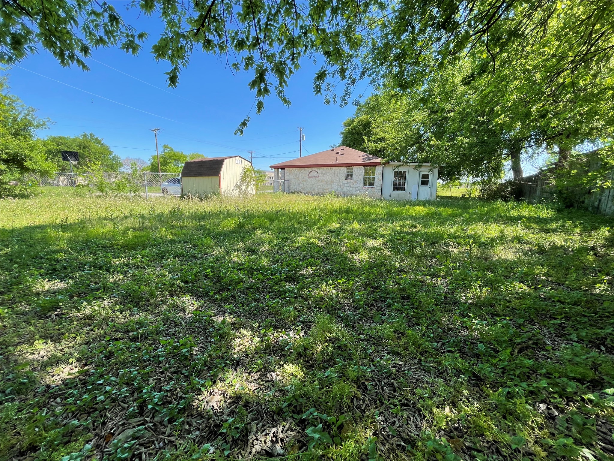 2004 Maple Street Georgetown, TX 78626 - Photo 29 of 31 Expansive backyard with a storage shed, established trees, and chain-link fencing