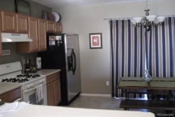 a kitchen with stainless steel appliances granite countertop a refrigerator a stove and a sink with wooden cabinets