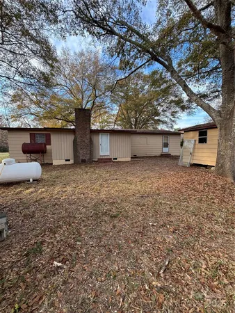 a backyard of a house with large trees and barbeque oven