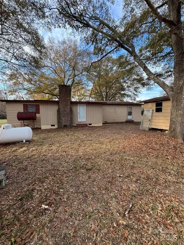 a backyard of a house with large trees and barbeque oven