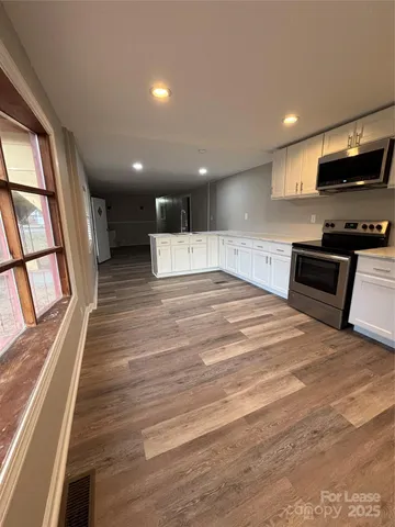 a large kitchen with stainless steel appliances granite countertop a stove a refrigerator a sink and a large window