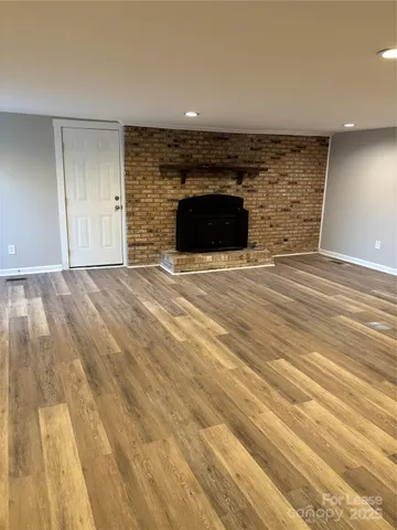 a view of empty room with wooden floor and fireplace
