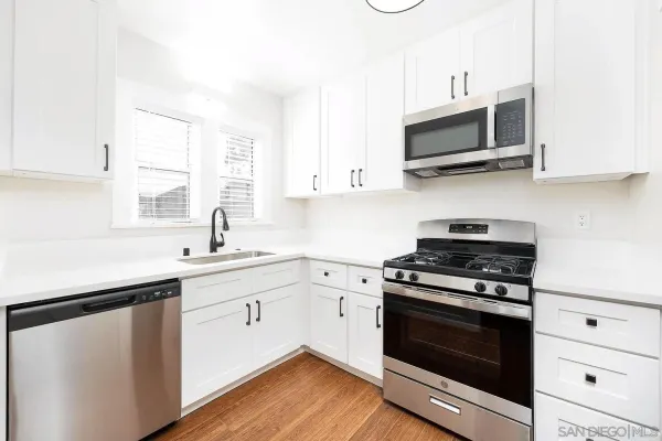 a kitchen with stainless steel appliances a white stove a sink and microwave with wooden floors