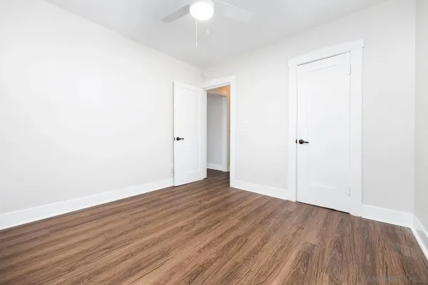 an empty room with wooden floor and a ceiling fan