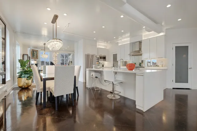 a room with stainless steel appliances kitchen island granite countertop a table chairs and a dining table with wooden floor