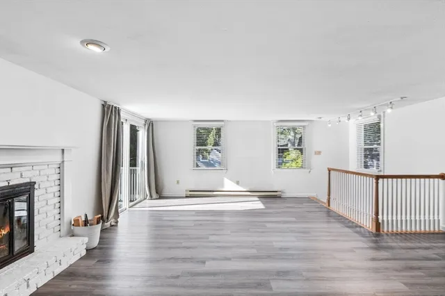 a view of a livingroom with wooden floor and a fireplace