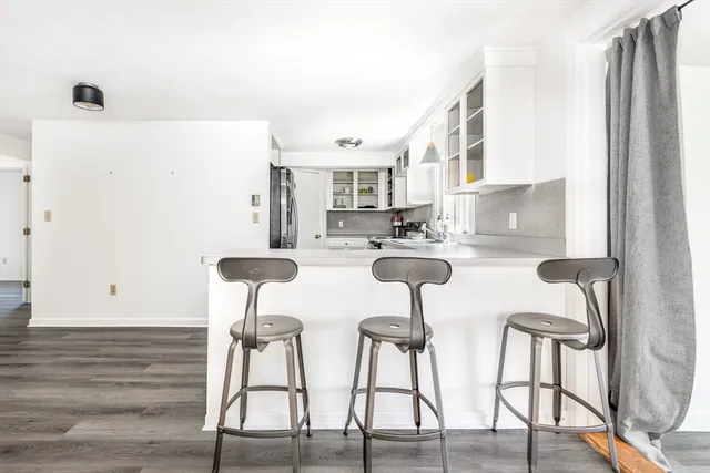 a kitchen with stainless steel appliances kitchen island granite countertop a dining table chairs and a refrigerator