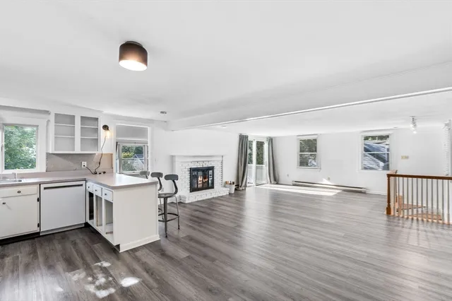 a view of a kitchen with a sink dishwasher a fireplace with wooden floor