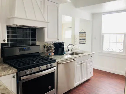 a kitchen with stainless steel appliances a stove a sink and white cabinets
