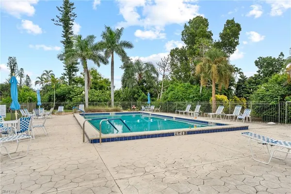 a view of swimming pool with lounge chair and dinning table under an umbrella