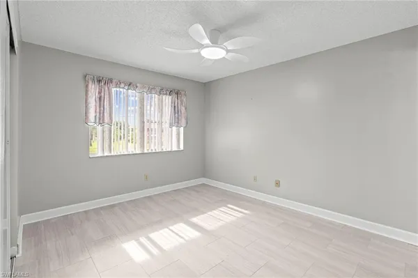 an empty room with windows and ceiling fan