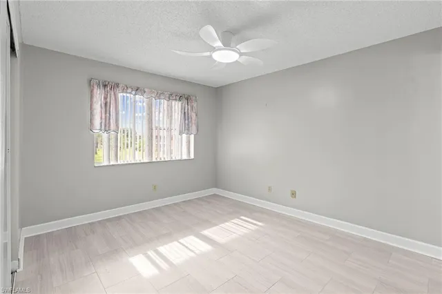 an empty room with windows and ceiling fan