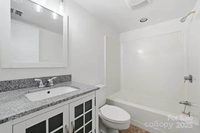 a bathroom with a granite countertop sink a toilet and shower