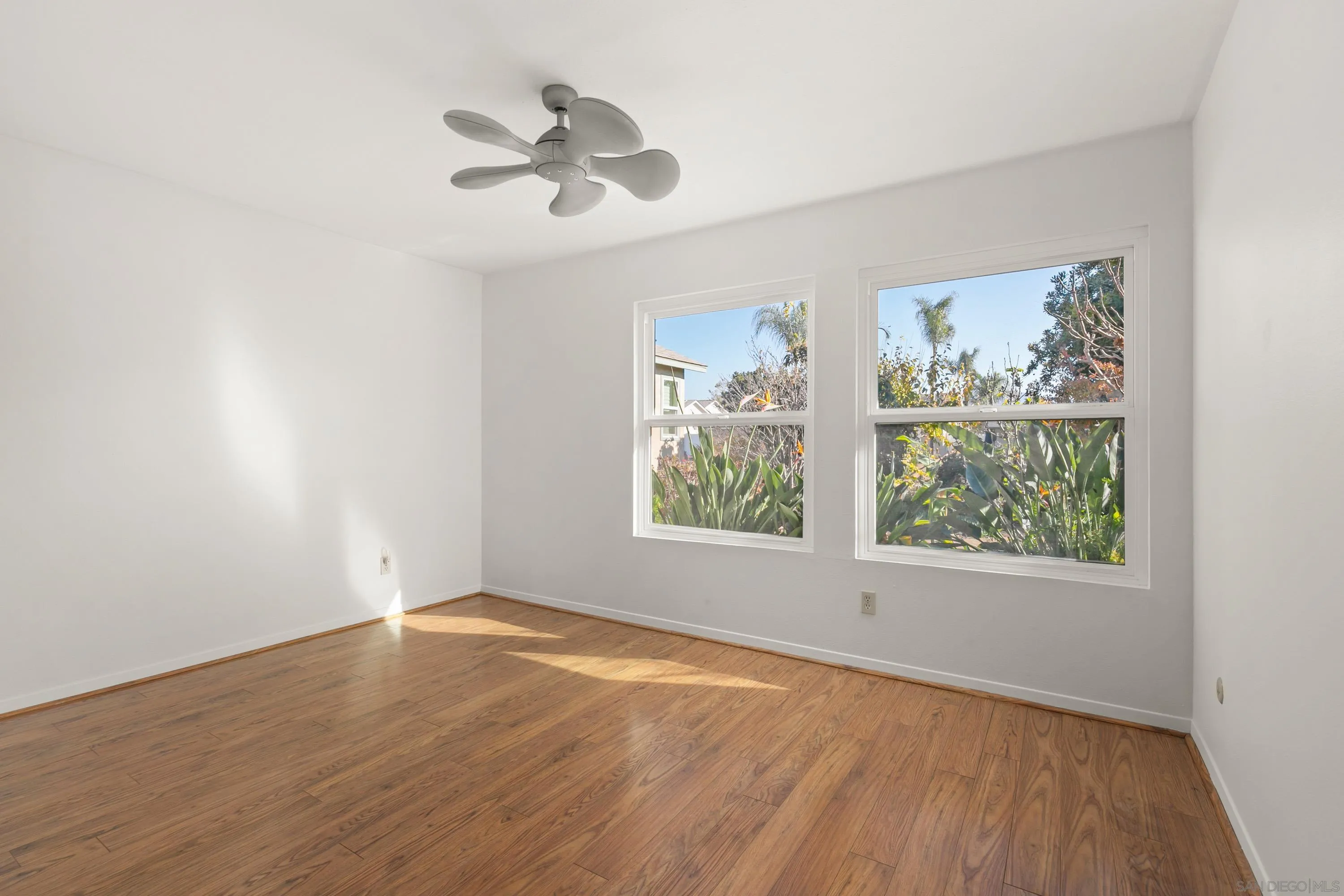 13840 Olive Grove Place Poway, CA 92064 - Photo 19 of 40 an empty room with wooden floor chandelier fan and windows