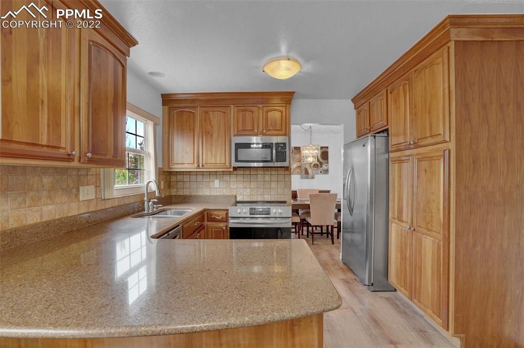 4930 Harvest Road Colorado Springs, CO 80917 - Photo 11 of 39 a kitchen with stainless steel appliances granite countertop a refrigerator a stove and a sink with wooden cabinets