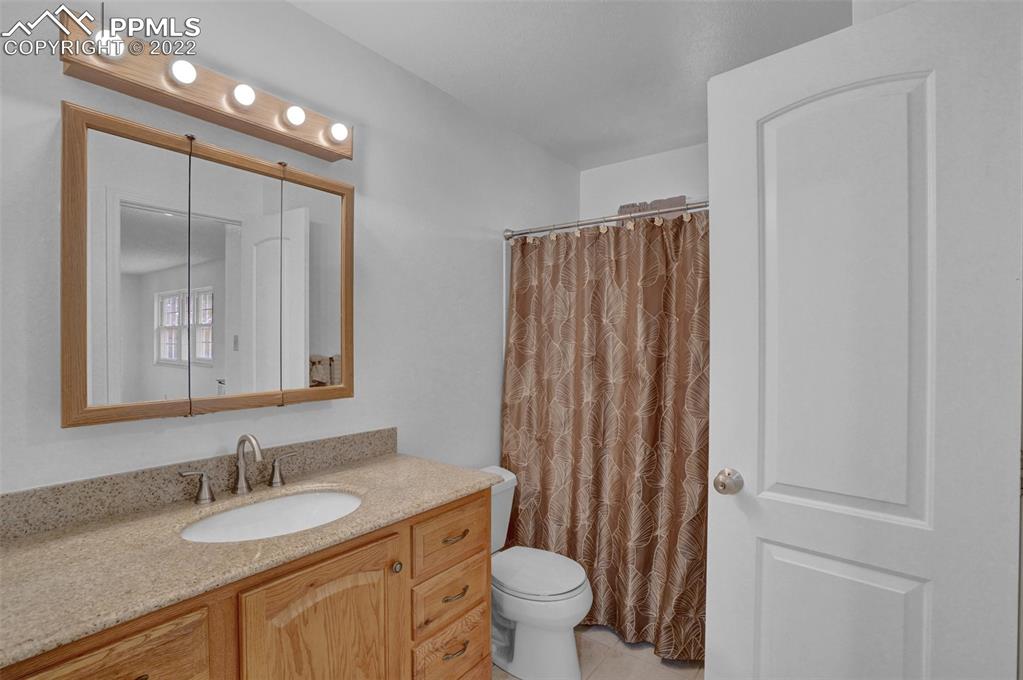 4930 Harvest Road Colorado Springs, CO 80917 - Photo 29 of 39 a bathroom with a granite countertop sink toilet and mirror