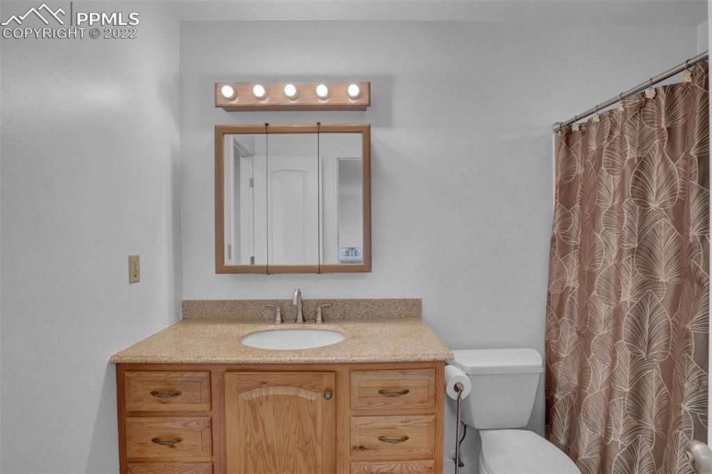 4930 Harvest Road Colorado Springs, CO 80917 - Photo 30 of 39 a bathroom with a granite countertop sink a toilet and a mirror