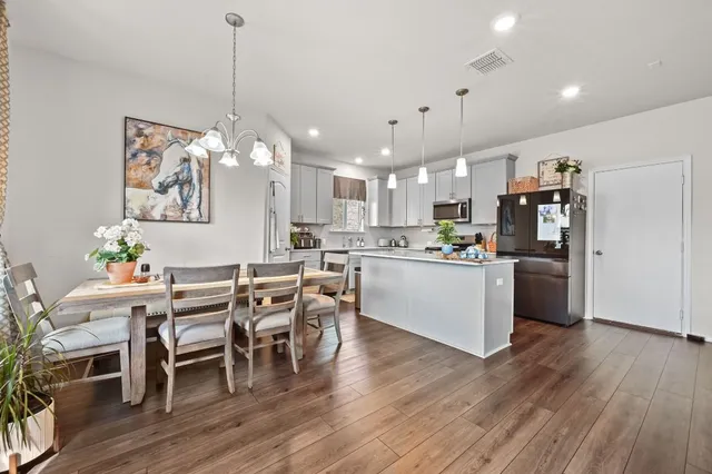 a view of a dining room and livingroom with furniture wooden floor a rug a chandelier and a view