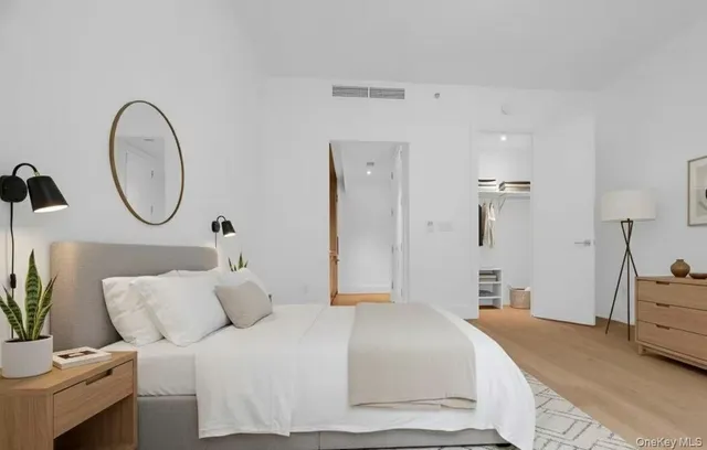 a bedroom with a bed a mirror and table chair