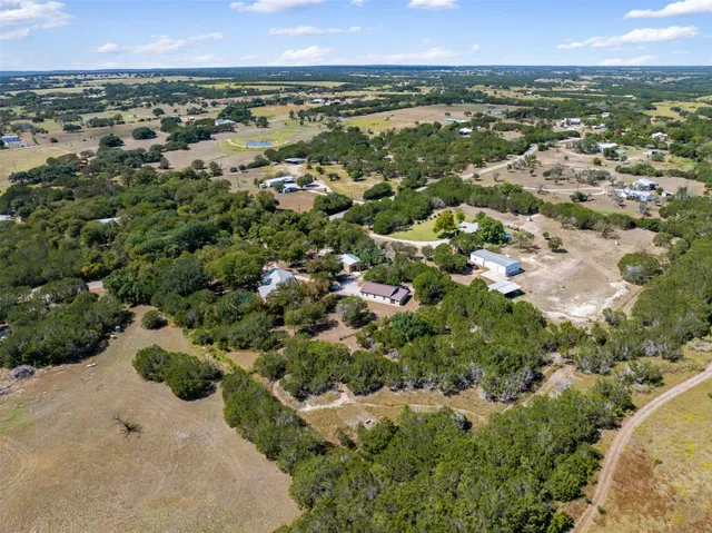 an aerial view of residential houses with outdoor space and trees