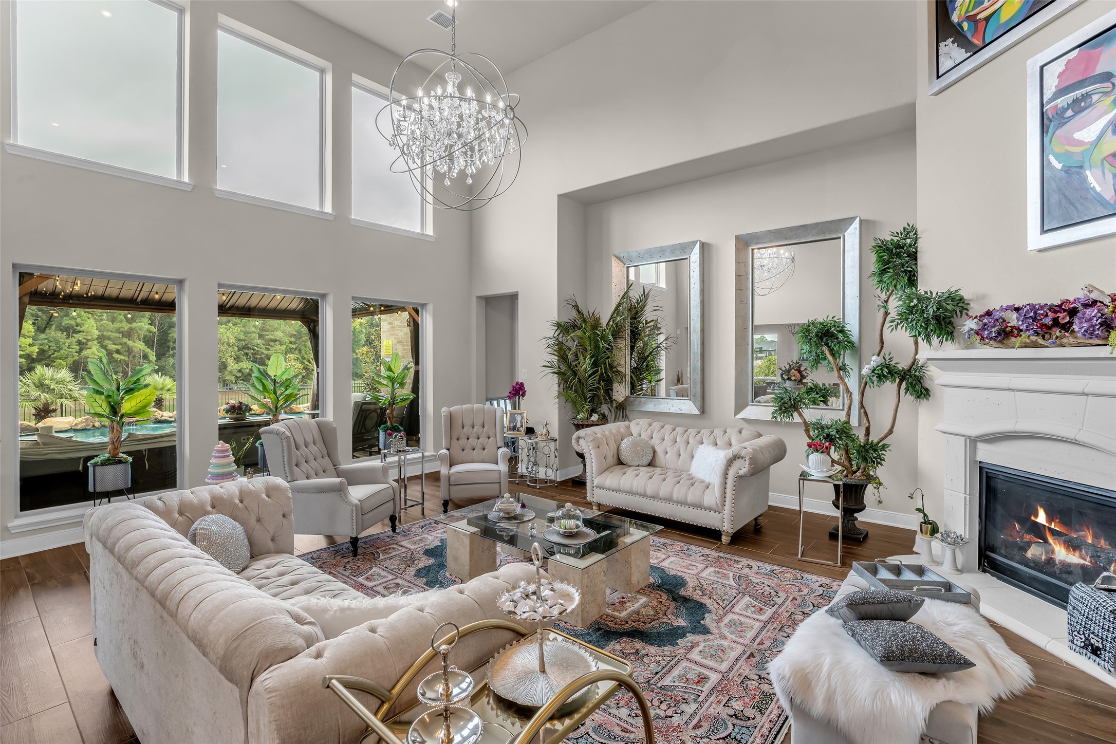 7211 Julie Pond Lane Spring, TX 77389 - Photo 9 of 45 Stunning living room with soaring ceilings, abundant natural light from large windows, elegant chandelier, cozy fireplace, and sophisticated seating area.