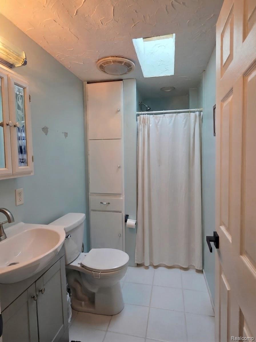 2611 Miller Road Allenton, MI 48002 - Photo 7 of 41 Bathroom featuring a vanity with a white basin sink, white tile flooring, a built-in shower, and a skylight