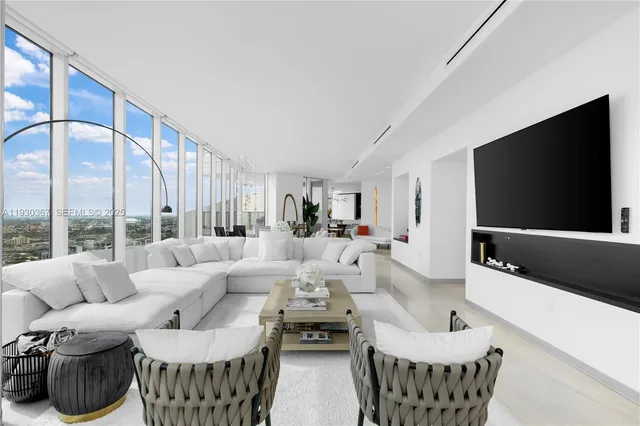 a living room with furniture a flat screen tv and a large window