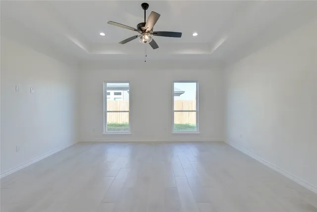 an empty room with wooden floor fan and windows
