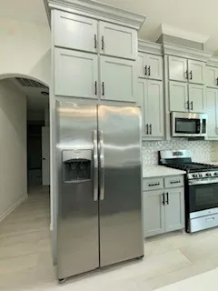 a metallic refrigerator freezer and a stove sitting inside of a kitchen