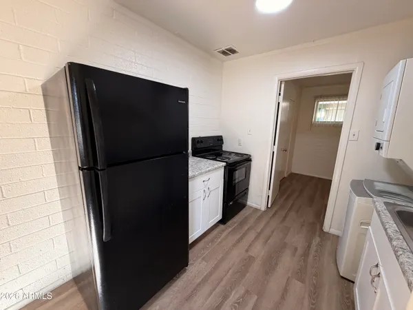 a kitchen with a refrigerator and wooden floor