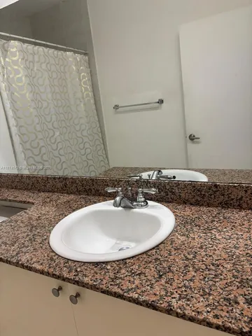 a bathroom with a granite countertop sink and a mirror