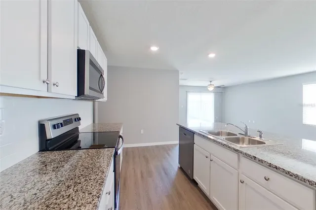 a spacious bathroom with kitchen island a sink granite counter tops and a wooden floor