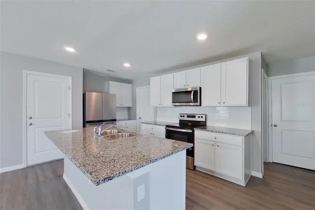 a kitchen with stainless steel appliances granite countertop a sink refrigerator and microwave