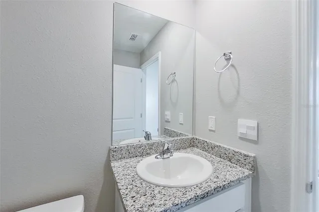 a bathroom with a granite countertop sink and a mirror