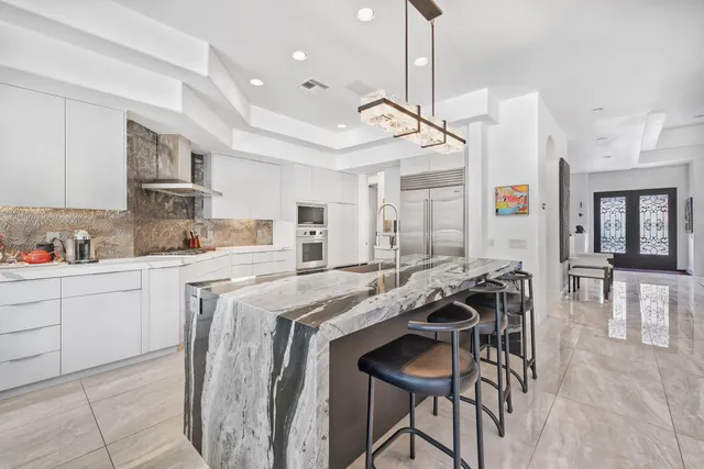 a kitchen with stainless steel appliances granite countertop a sink a stove a refrigerator and island