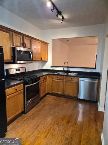 a kitchen with stainless steel appliances granite countertop a sink cabinets and wooden floor