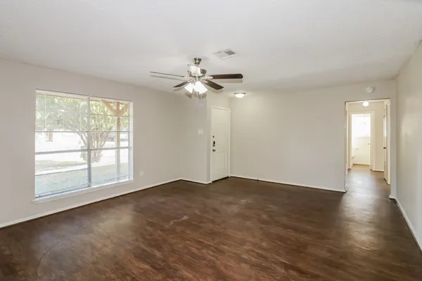 a view of empty room with wooden floor and window
