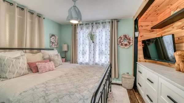 a bedroom with a large bed and a flat tv screen on dresser