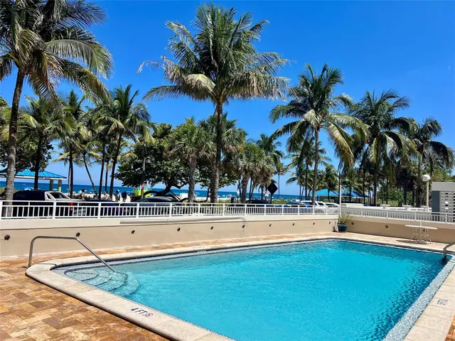 a view of a swimming pool with a lawn chair and palm tree